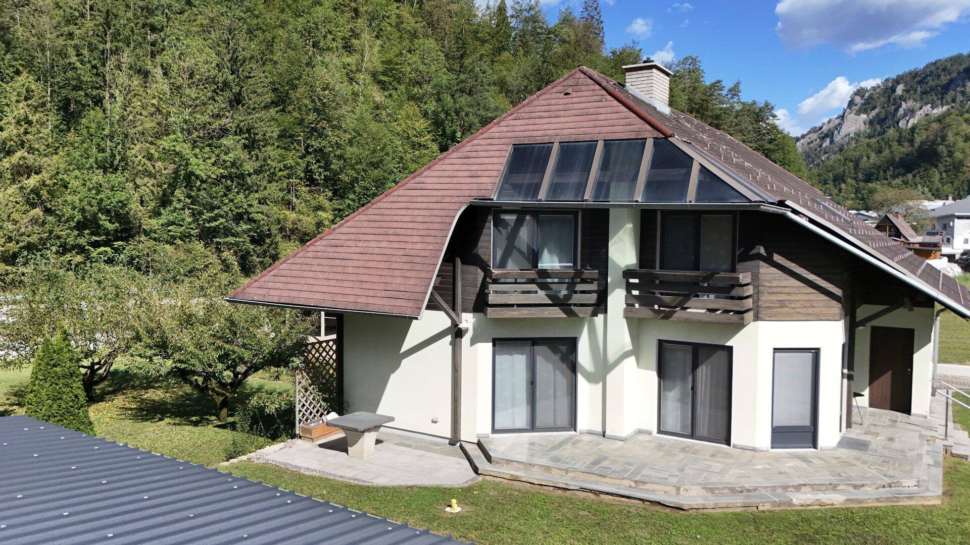 Attraktives Einfamilienhaus mit Terrasse, Solaranlage auf dem Dach und umgeben von grüner Natur.