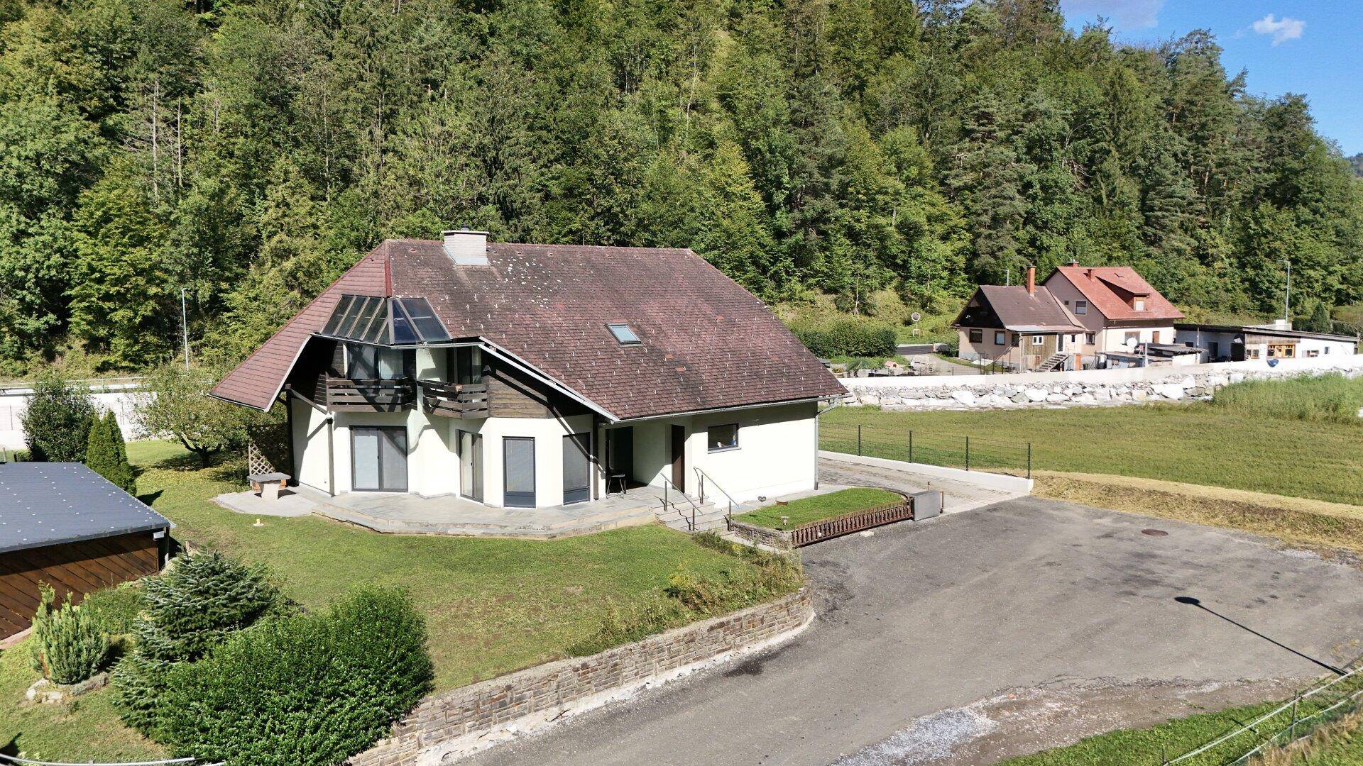 Freistehendes Haus mit großer Terrasse, umgeben von üppiger Natur und einem weiten Blick.