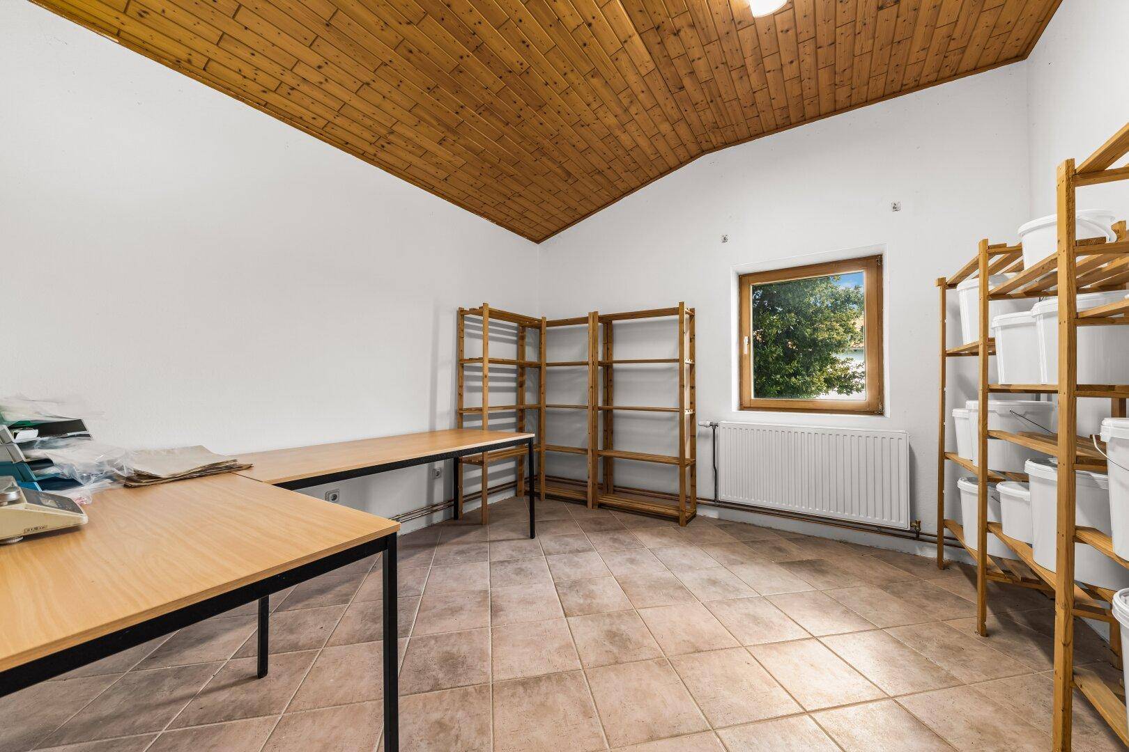 Funktionaler Raum mit Holzdecke, braunen Fliesen und praktischen Holzregalen für Lagerung.
