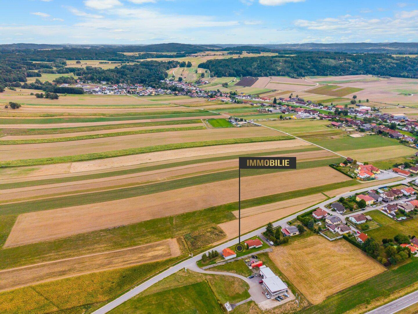 Weitläufige Luftaufnahme der Immobilie eingebettet in eine ländliche Landschaft mit Feldern.