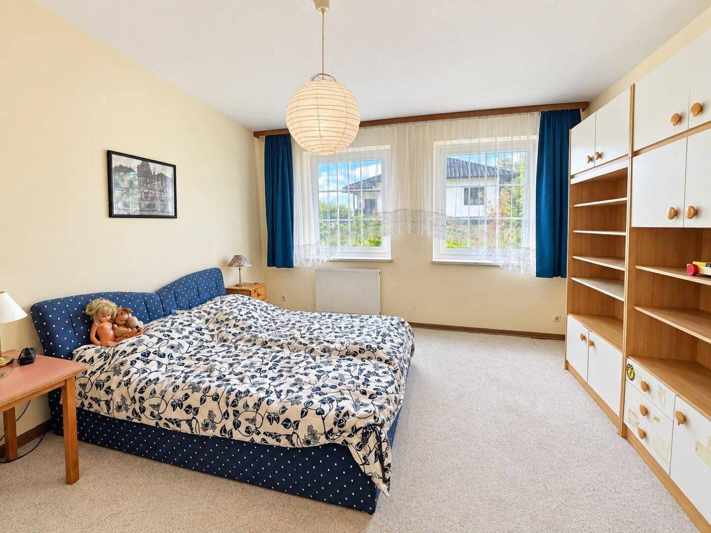 Schlafzimmer mit Doppelbett, Teppichboden und hellen Wänden.