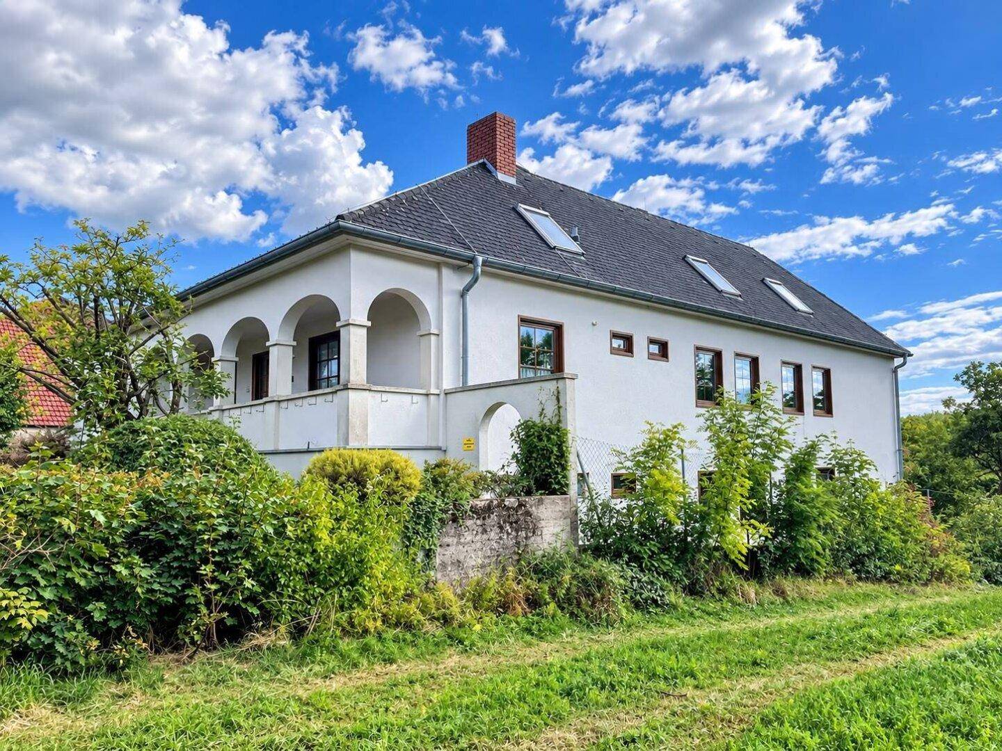 Seitenansicht des Hauses mit Arkaden und Blick auf die umgebende Natur.