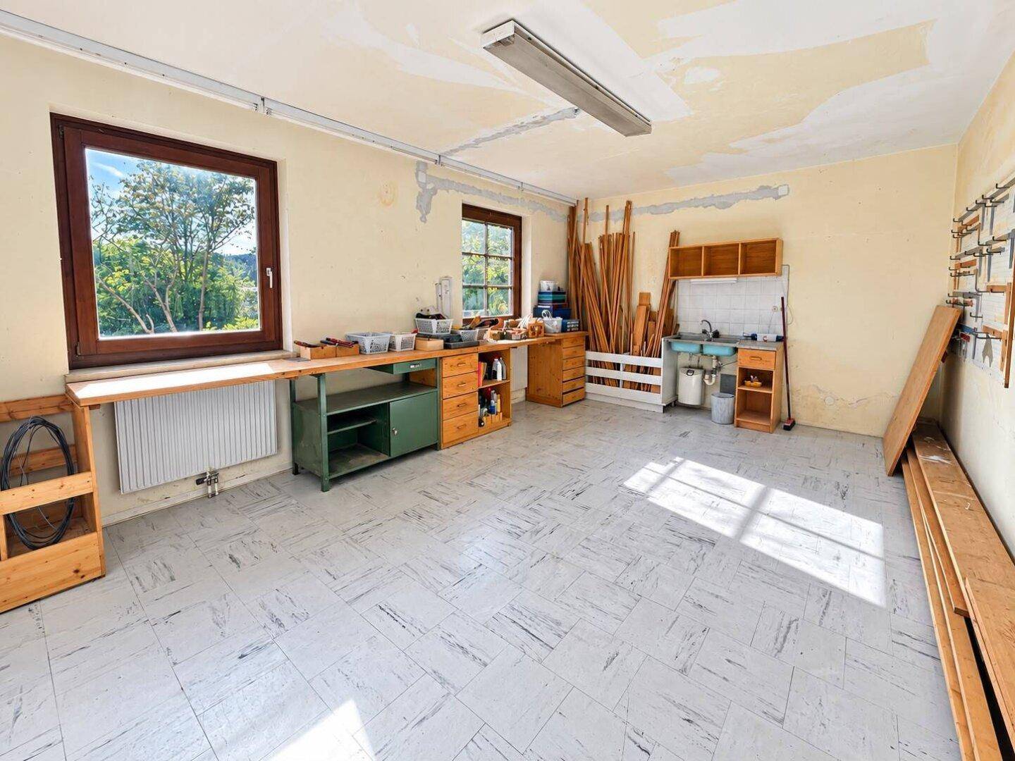Helle Werkstatt mit Arbeitsflächen, Stauraum und Blick ins Grüne.