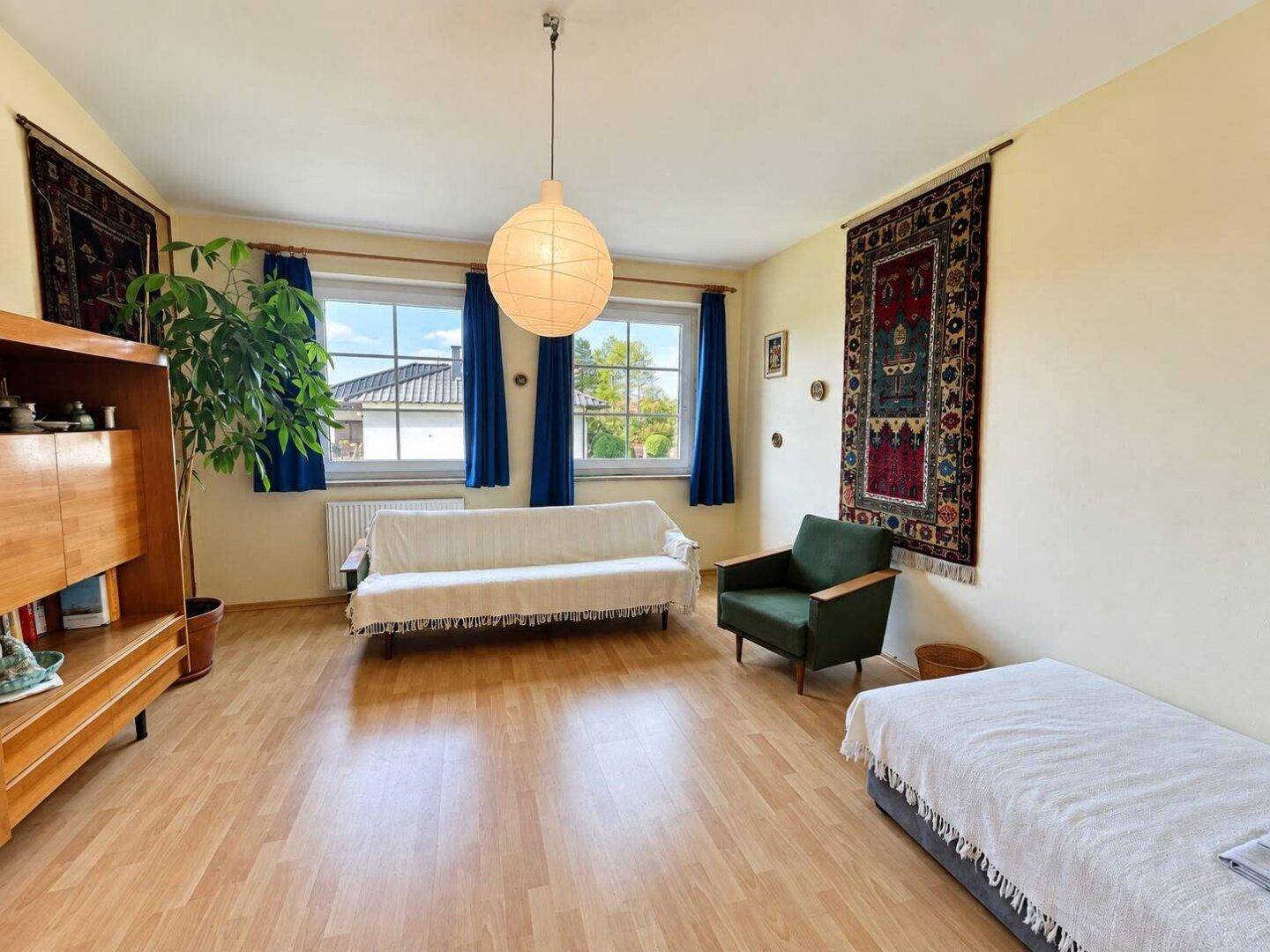 Gemütlicher Raum mit Laminatboden, Sofa und dekorativen Wandteppichen.
