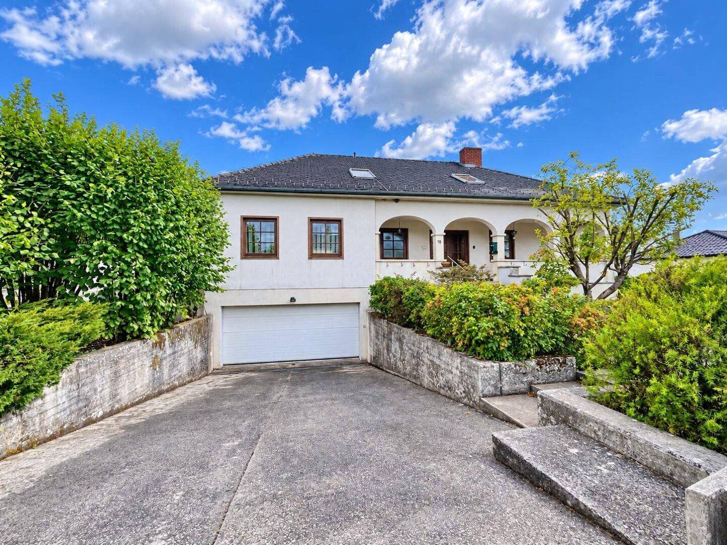 Vorderansicht des Hauses mit integrierter Garage und gepflasterter Auffahrt.