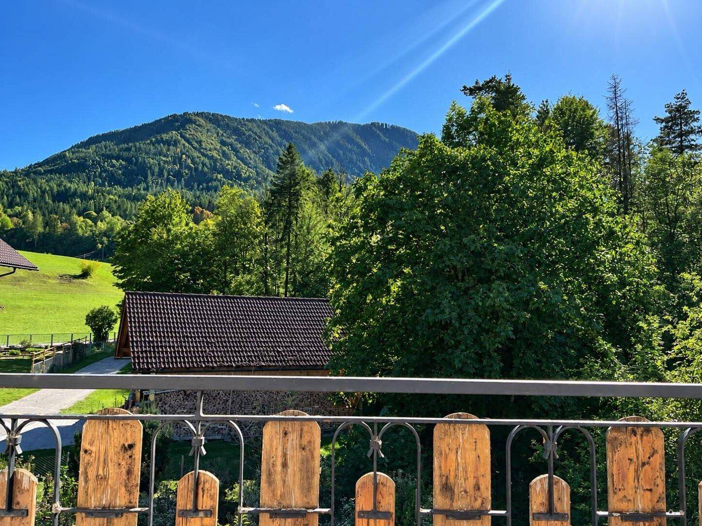 Panoramablick vom Balkon auf die umliegende Berglandschaft und grüne Wälder.