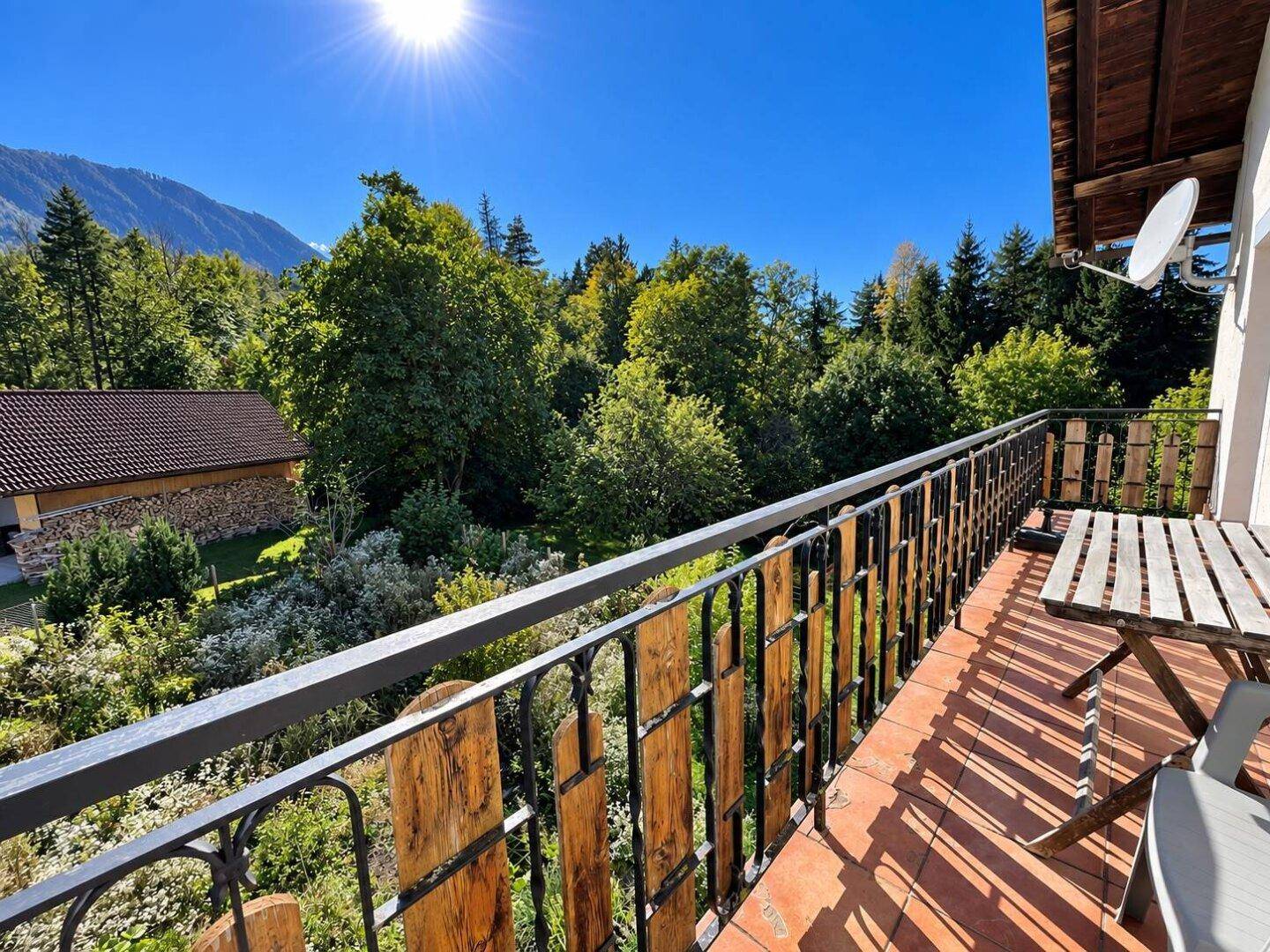 Geräumiger Balkon mit rustikalem Holzgeländer und Blick auf die grüne Natur.