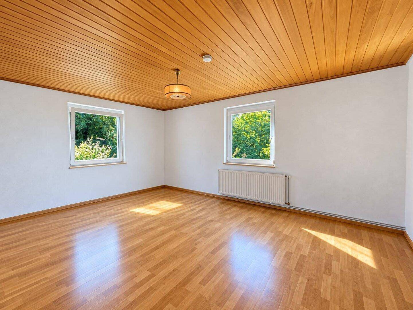 Geräumiges, helles Zimmer mit Holzdecke und Parkettboden, ideal für Wohnzwecke.