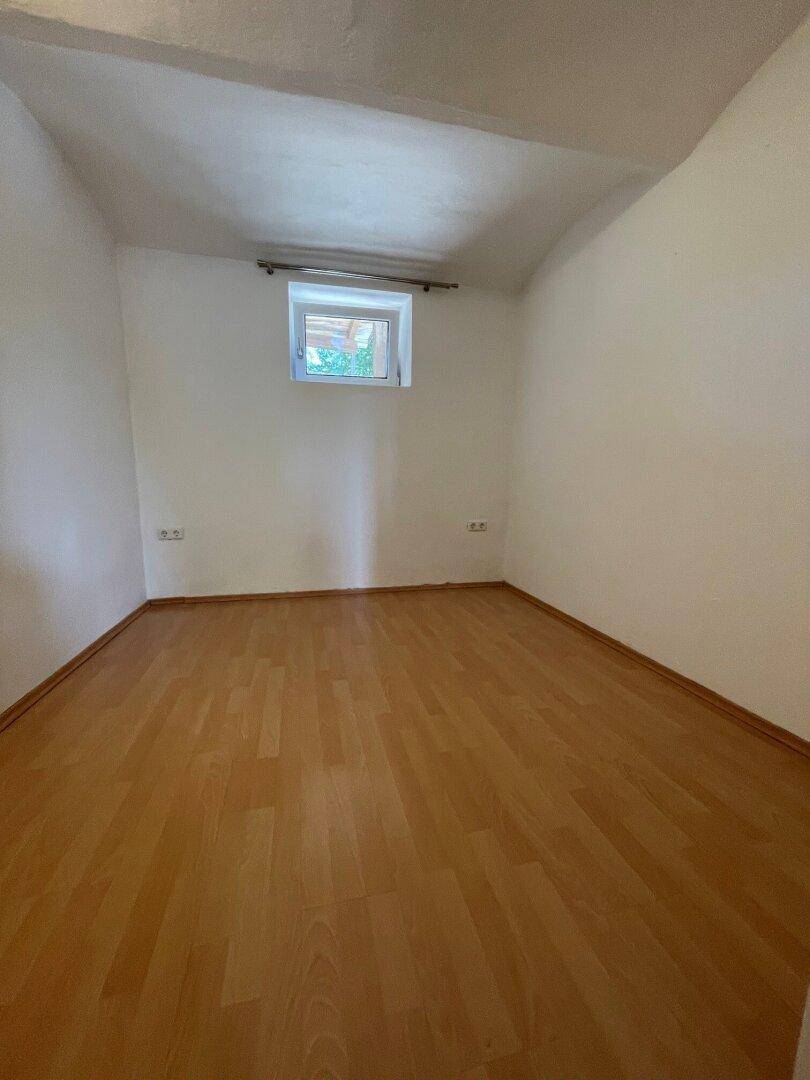 Helles Zimmer mit Laminatboden und kleinem Fenster, ideal als Schlaf- oder Gästezimmer.