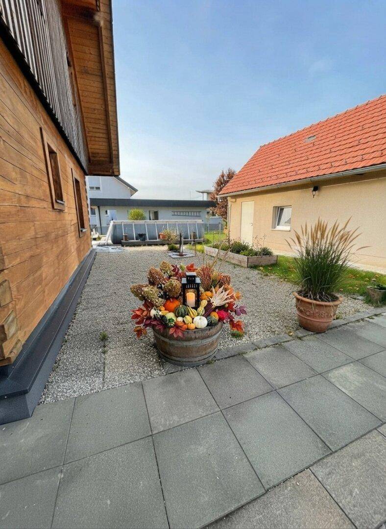 Seitenbereich des Hauses mit Kiesfläche und herbstlicher Fassadendekoration.
