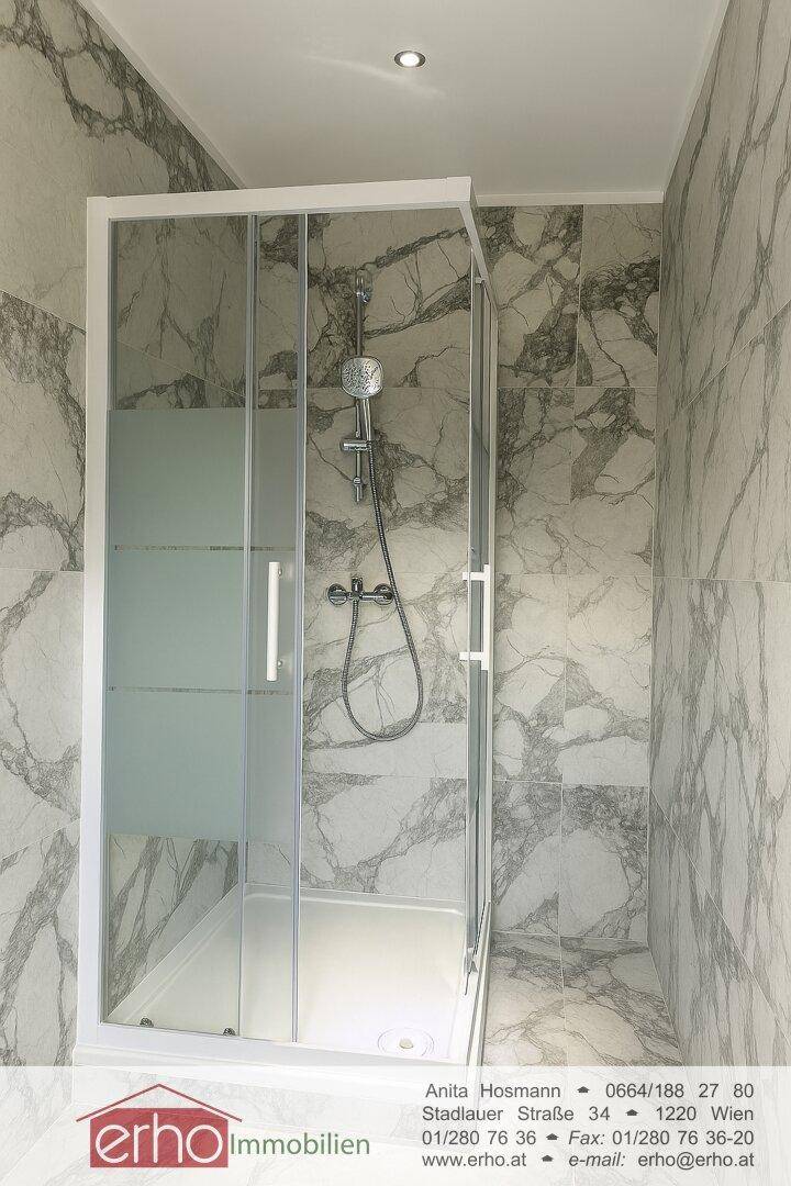 Modernes Badezimmer mit Duschkabine und Marmoroptik-Fliesen an Wänden und Boden.