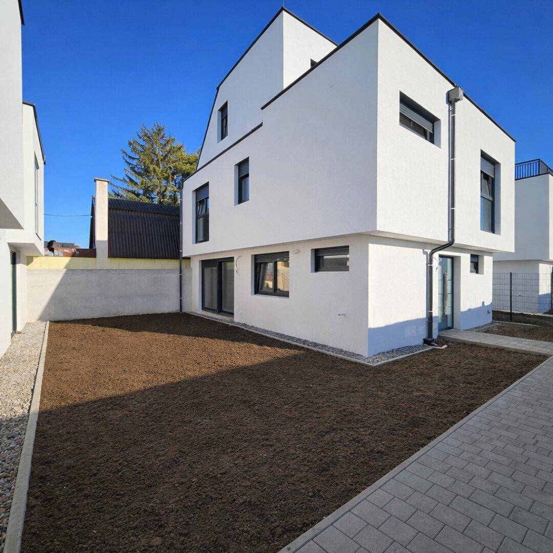 Modernes Gebäude mit ungestaltetem Gartenbereich, bereit für die individuelle Landschaftsgestaltung.