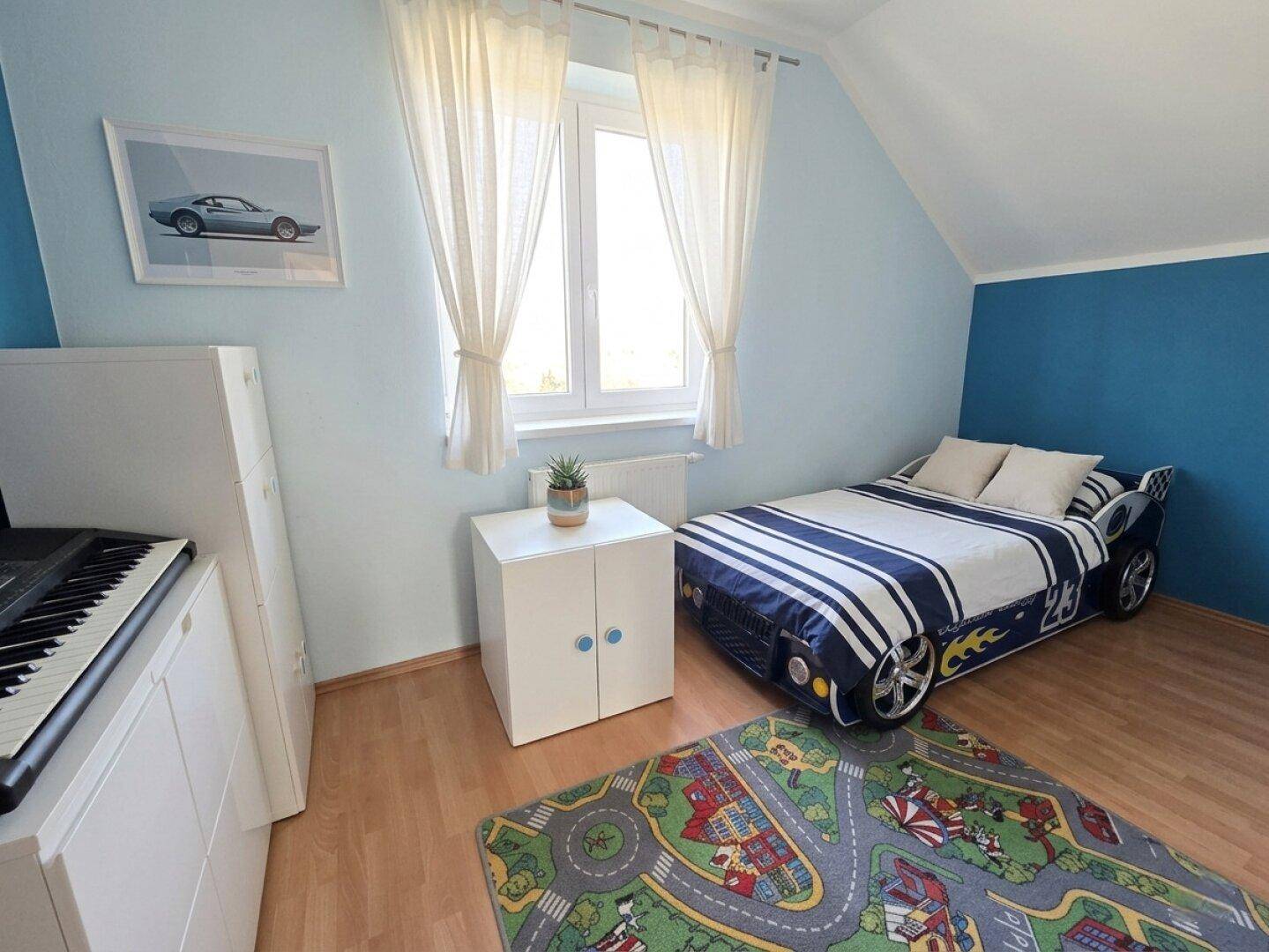 Kinderzimmer mit blau gestrichenen Wänden, Holzboden und einem Rennauto-Bett.