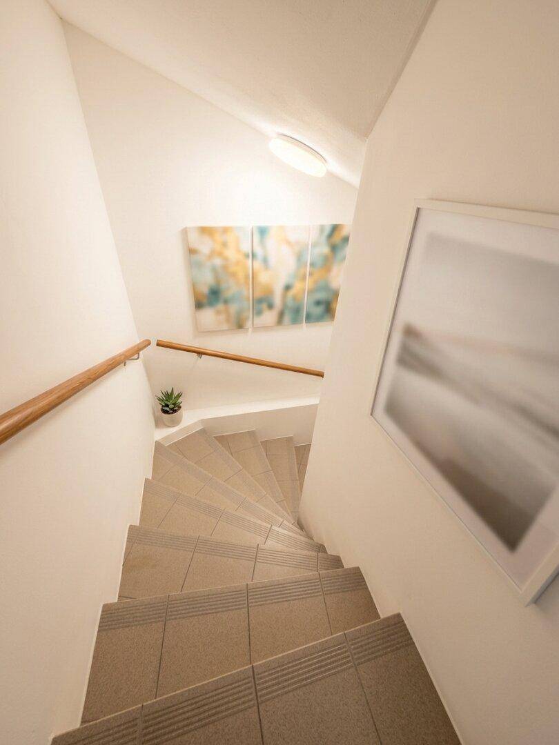 Treppenabgang zum Keller mit gefliesten Stufen und heller Wandgestaltung.
