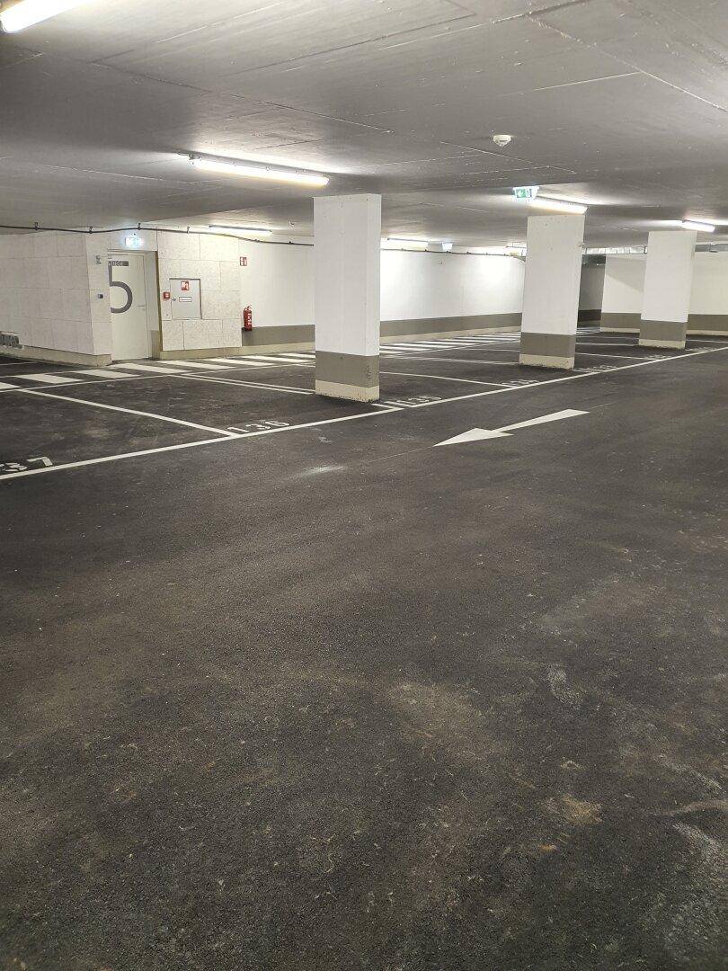 Moderne Tiefgarage mit dunklem Asphaltboden und klar markierten Parkplätzen.
