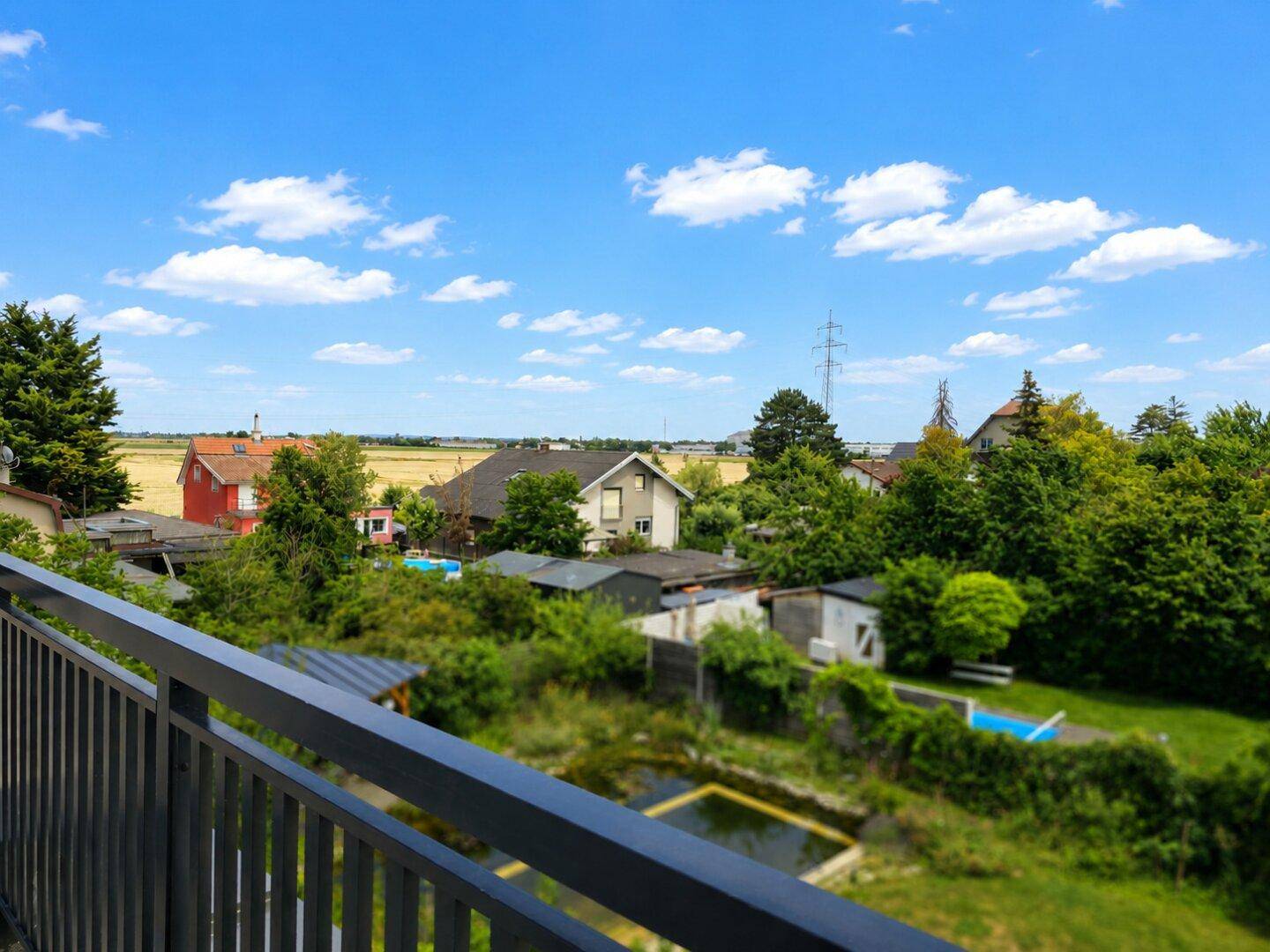 Weitläufiger Ausblick von der Terrasse auf die ländliche Umgebung mit Häusern und Feldern.
