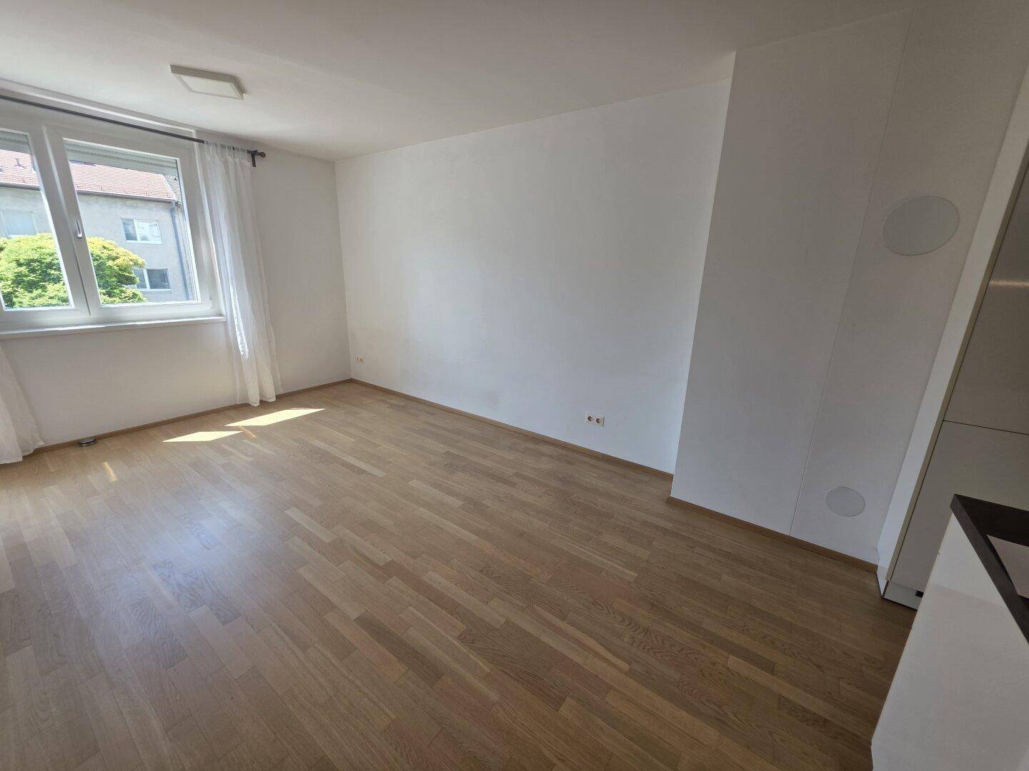 Geräumiges Schlafzimmer mit hellem Parkettboden und großem Fenster, gut belichtet.