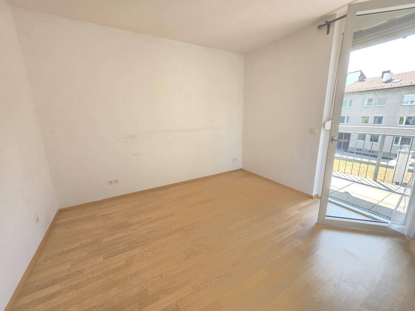 Helles Zimmer mit Parkettboden und direktem Zugang zu einem sonnigen Balkon.