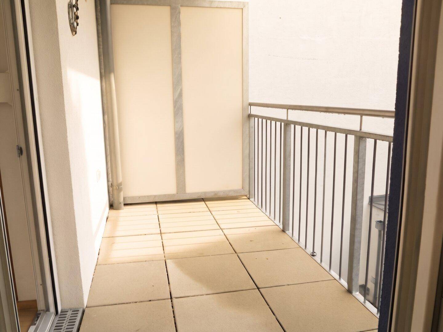 Heller Balkon mit Fliesenboden und Metallgeländer, ideal für entspannte Stunden im Freien.