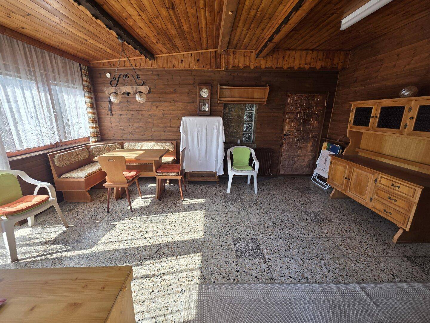 Heller Wintergarten mit Holzwänden und -decke, Essbereich und traditionellen Möbeln.