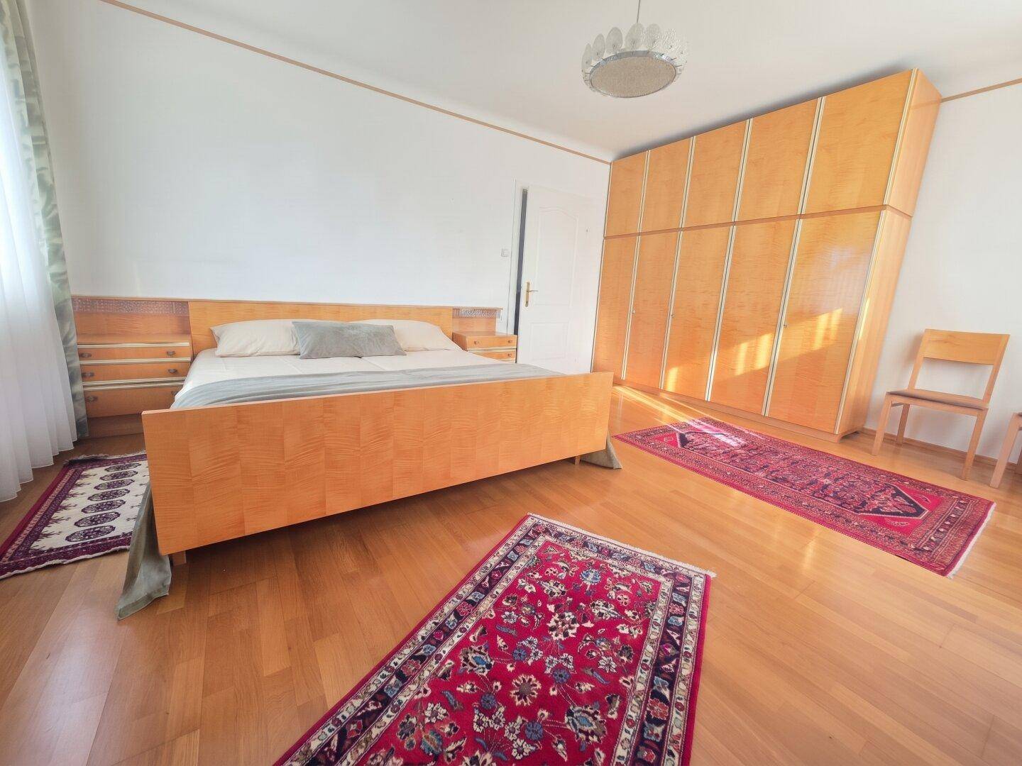 Schlafzimmer mit hellem Holzparkett, großem Bett und passendem Kleiderschrank.