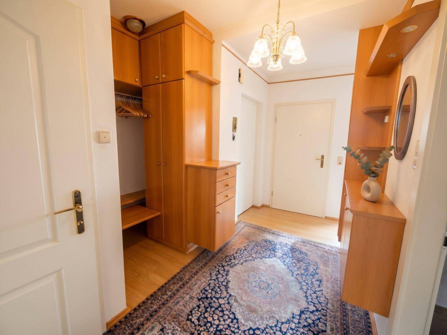 Eingangsbereich mit Holzparkett, integrierten Garderobenschränken und Spiegel.