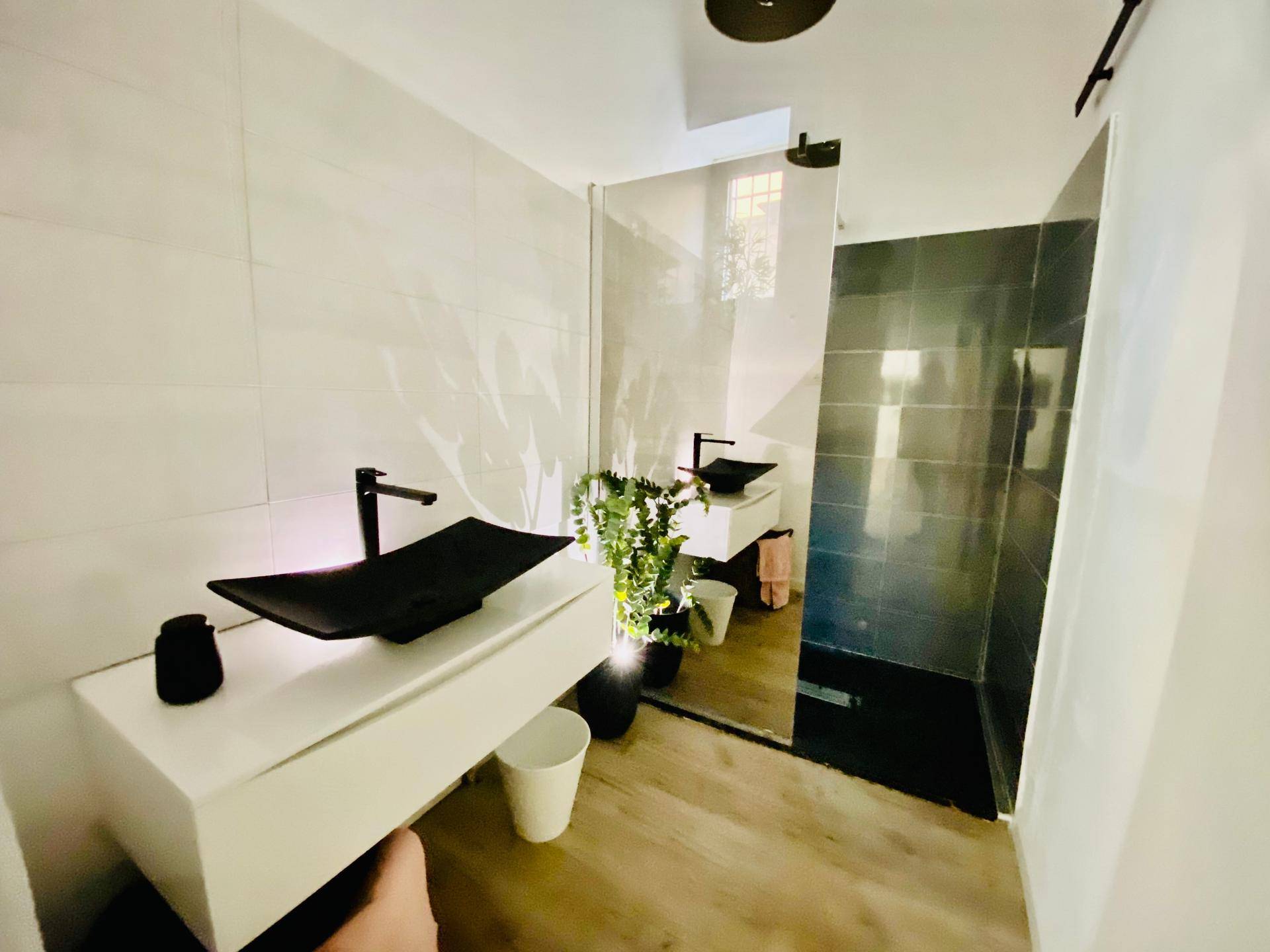 Modernes Badezimmer mit dunklen Armaturen, zwei Waschbecken und einer begehbaren Dusche.