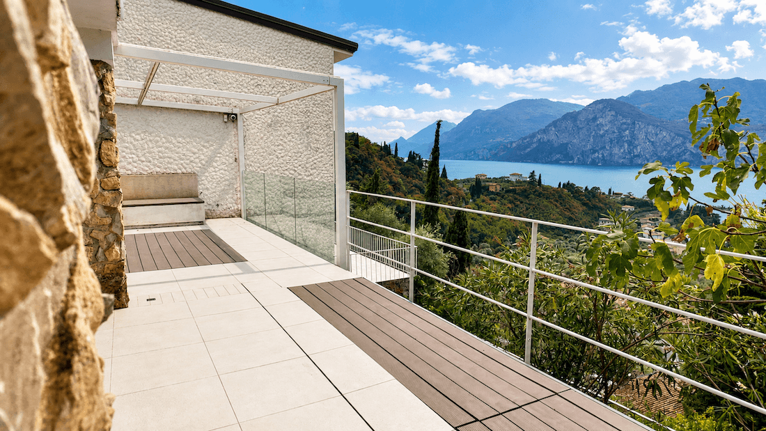 Geräumige Terrasse mit Fliesen und Holz, einer Pergola und einem weiten Blick über den See und die Landschaft.