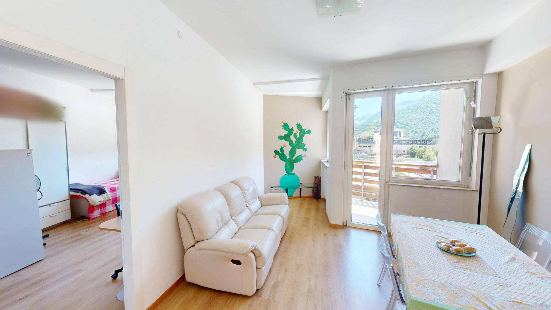 Geräumiges Wohn- und Esszimmer mit beigem Sofa, Holzboden und Blick auf die Berge.