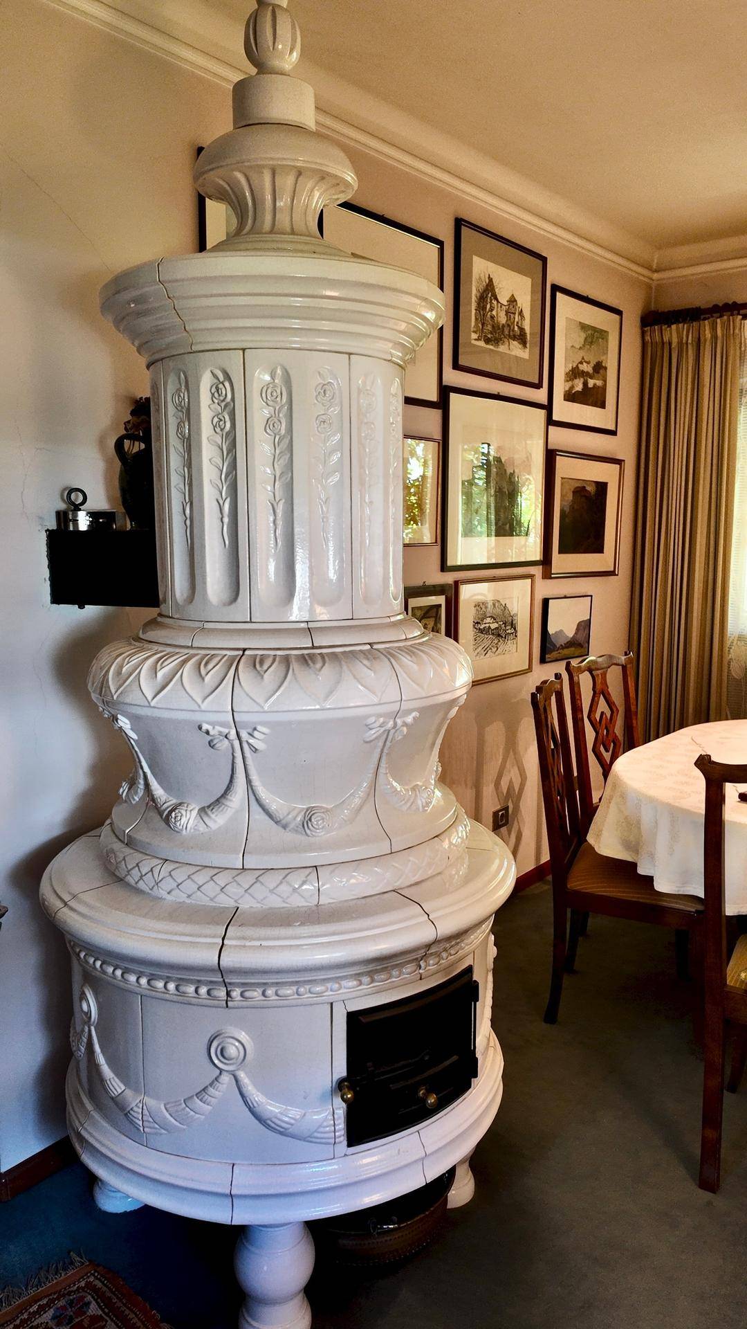 Detailansicht eines prächtigen weißen Kachelofens in einem traditionellen Esszimmer.
