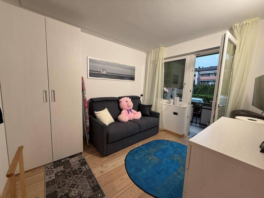Gemütliches Schlafzimmer mit Schlafsofa, Kleiderschrank und Zugang zu einem kleinen Balkon.