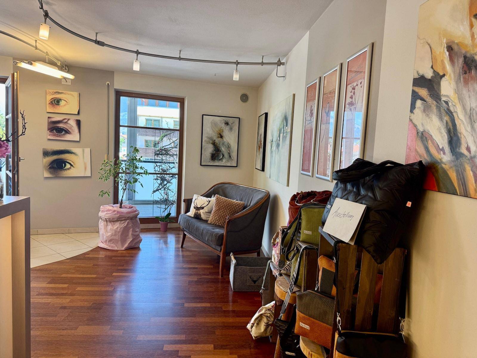 Gemütlicher Wartebereich mit Sofa, verschiedenen Kunstwerken und Blick auf die Umgebung.