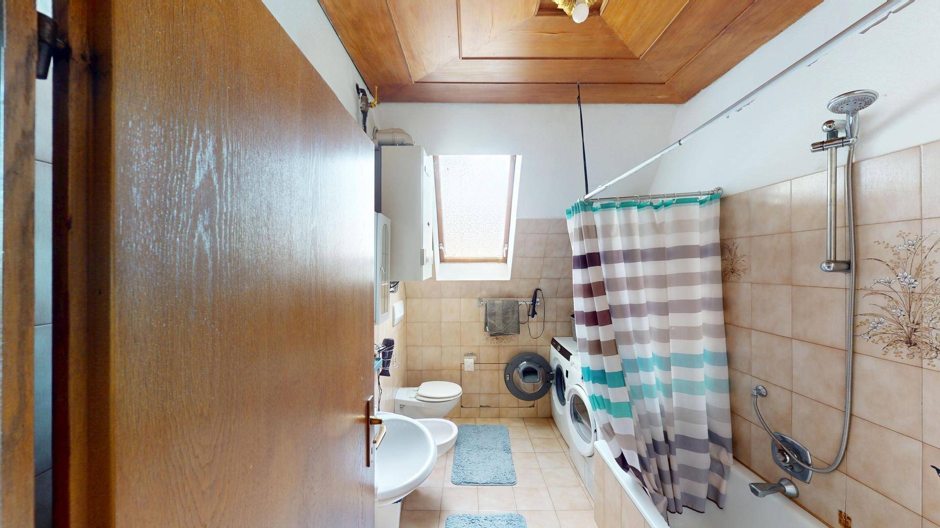Badezimmer mit Badewanne, Dusche, Waschbecken, Toilette und einem Dachfenster.