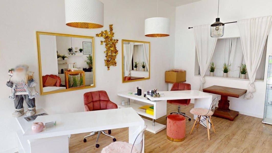 Heller Arbeitsbereich mit weißen Schreibtischen, goldenen Spiegeln und festlicher Dekoration.