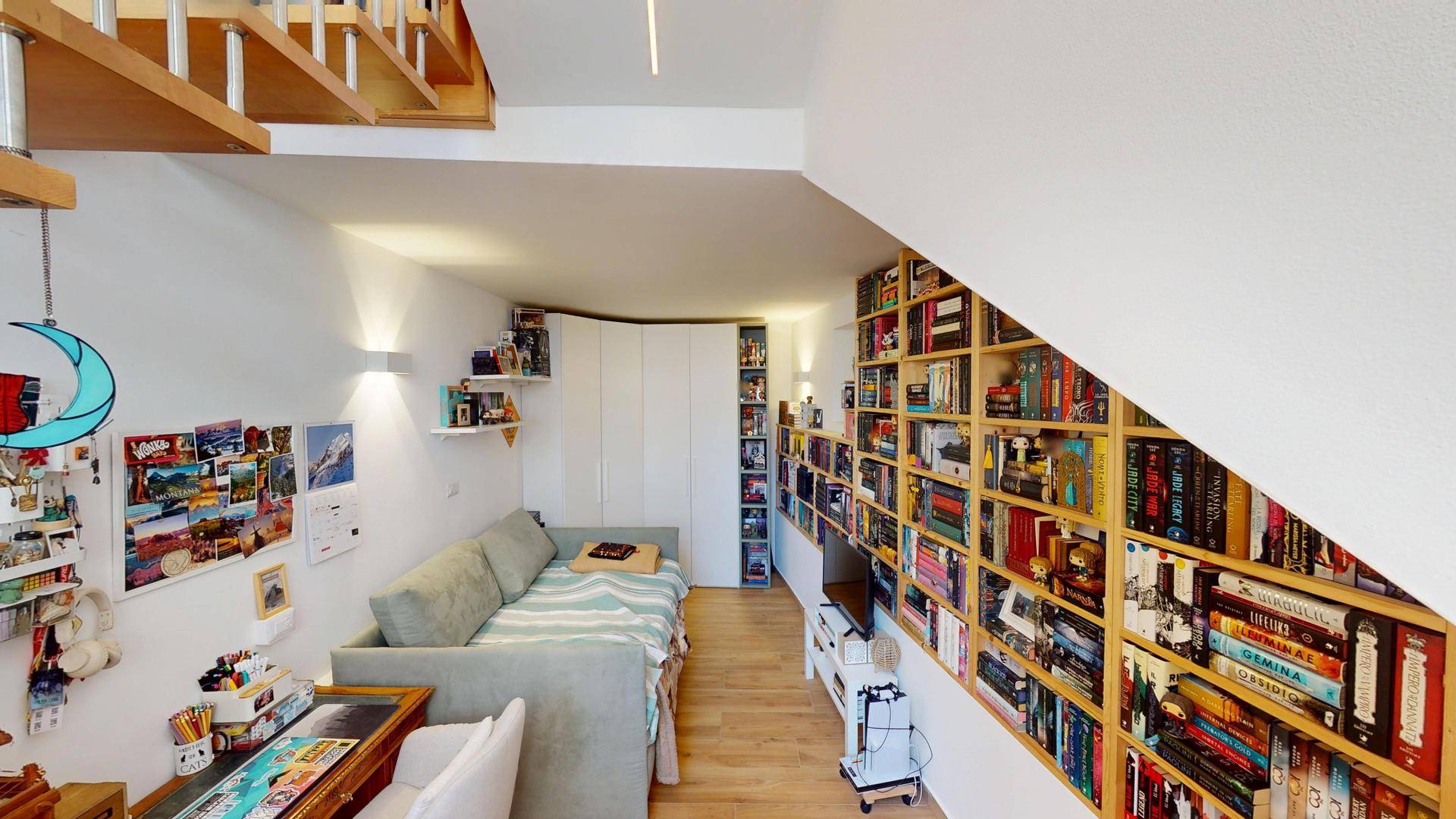 Gemütlicher Wohnbereich mit Sofa, Bücherregalen und Treppenaufgang.