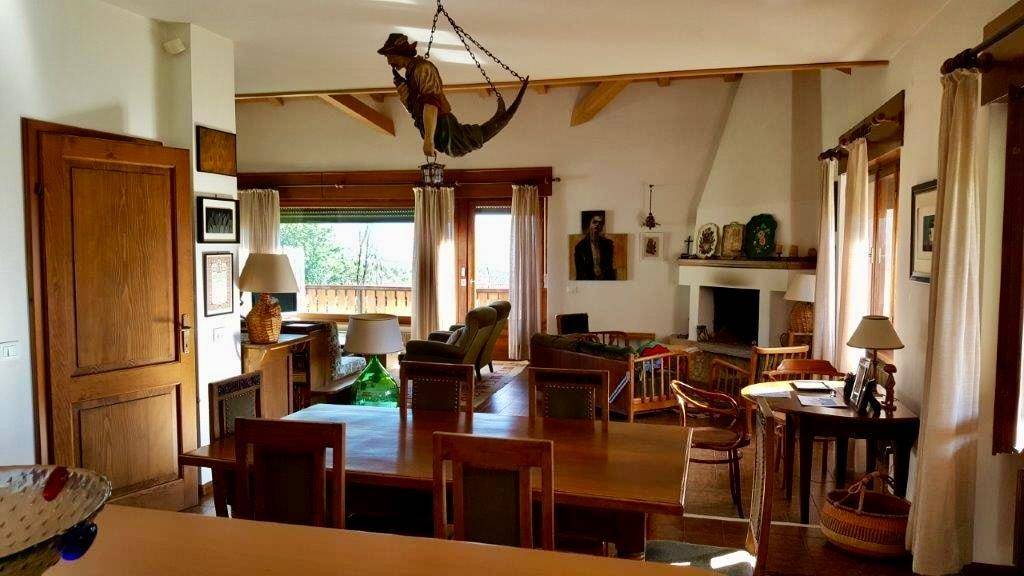 Offener Wohn- und Essbereich mit Kamin, Holzbalken und Zugang zum Außenbereich.