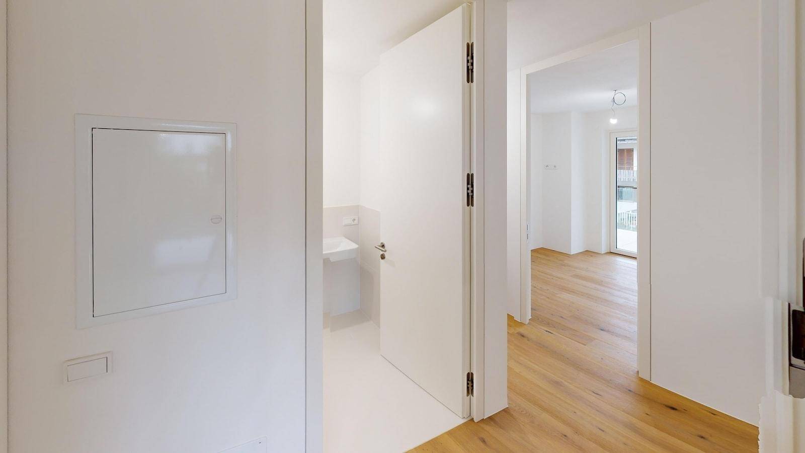 Eingangsbereich mit Blick auf eine moderne Gästetoilette mit Fliesenboden.
