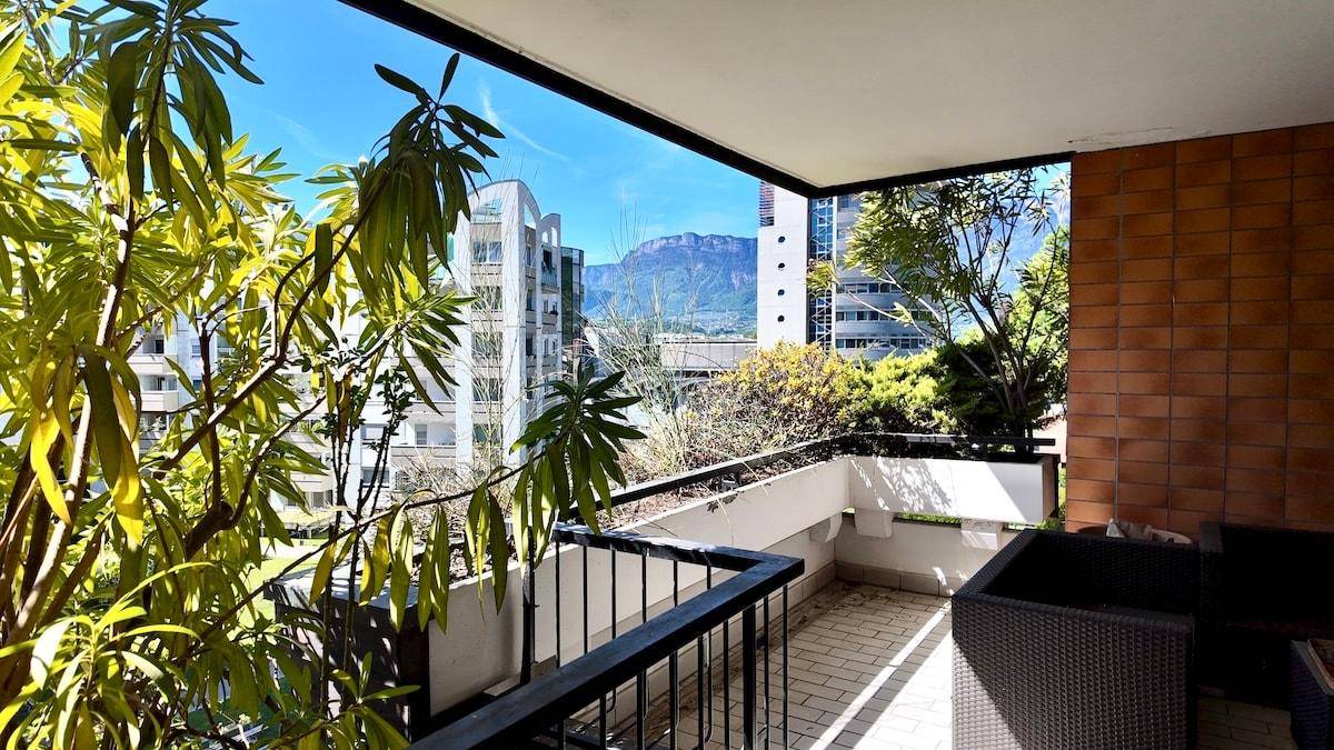 Balkon mit Pflanzen und weitem Blick auf die umliegenden Gebäude und die Berge.