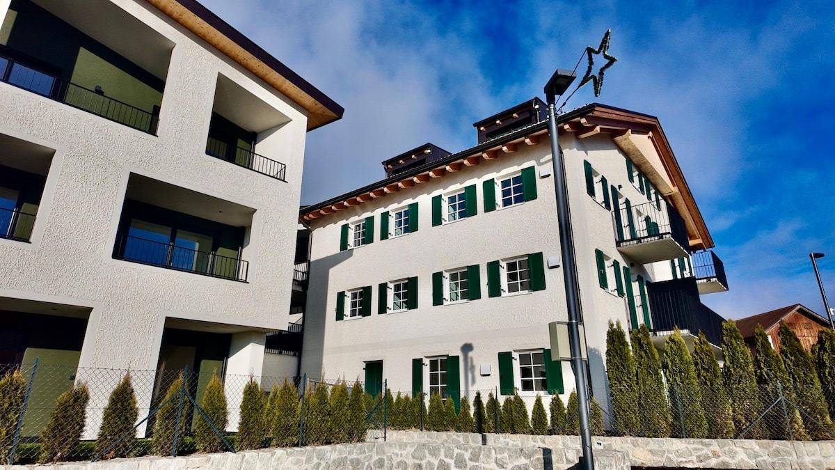 Zwei Wohngebäude mit unterschiedlicher Architektur, umgeben von grünen Hecken.