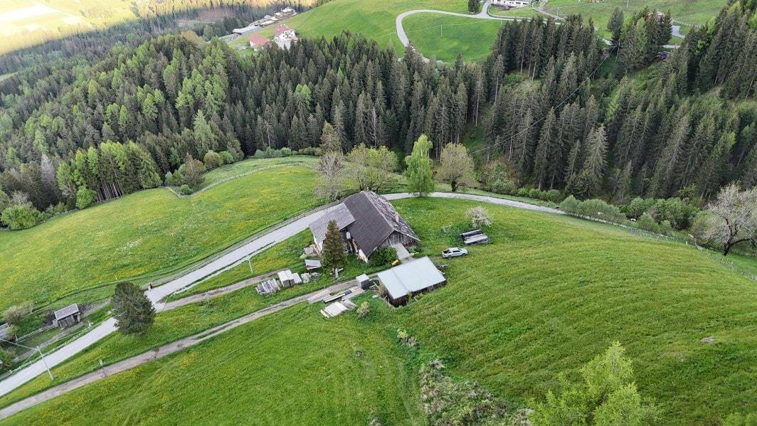 Luftaufnahme eines ländlichen Anwesens mit traditionellen Gebäuden, umgeben von grünen Terrassenfeldern.