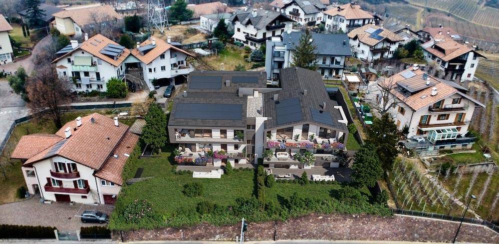 Luftaufnahme einer modernen Wohnanlage mit umliegenden Häusern und Weinbergen in der Natur.
