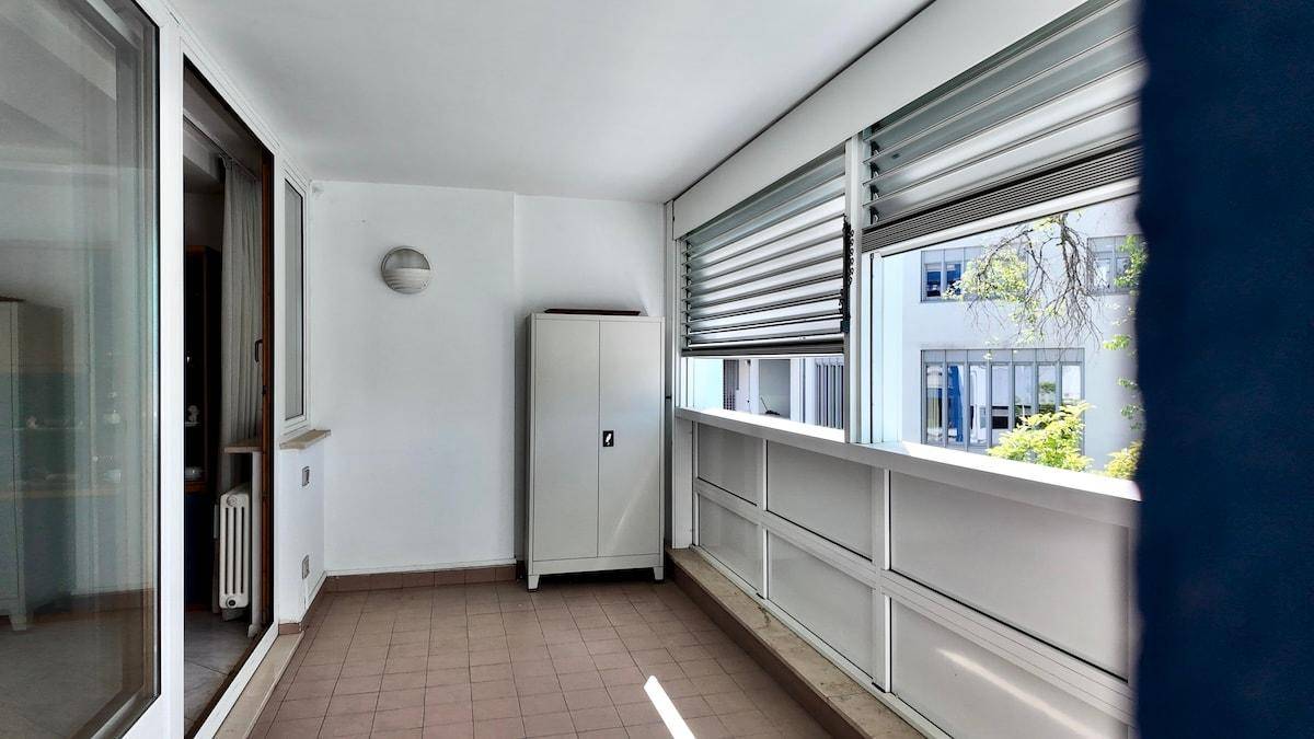 Verglaste Loggia mit Fliesenboden, Schrank und Blick auf die Umgebung.