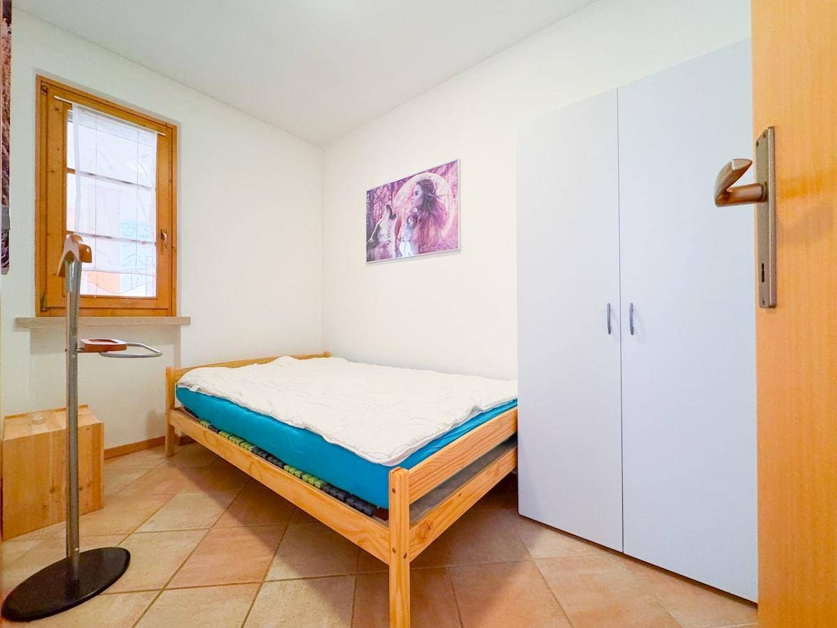 Helles Schlafzimmer mit Einzelbett, weißem Kleiderschrank und Fliesenboden.