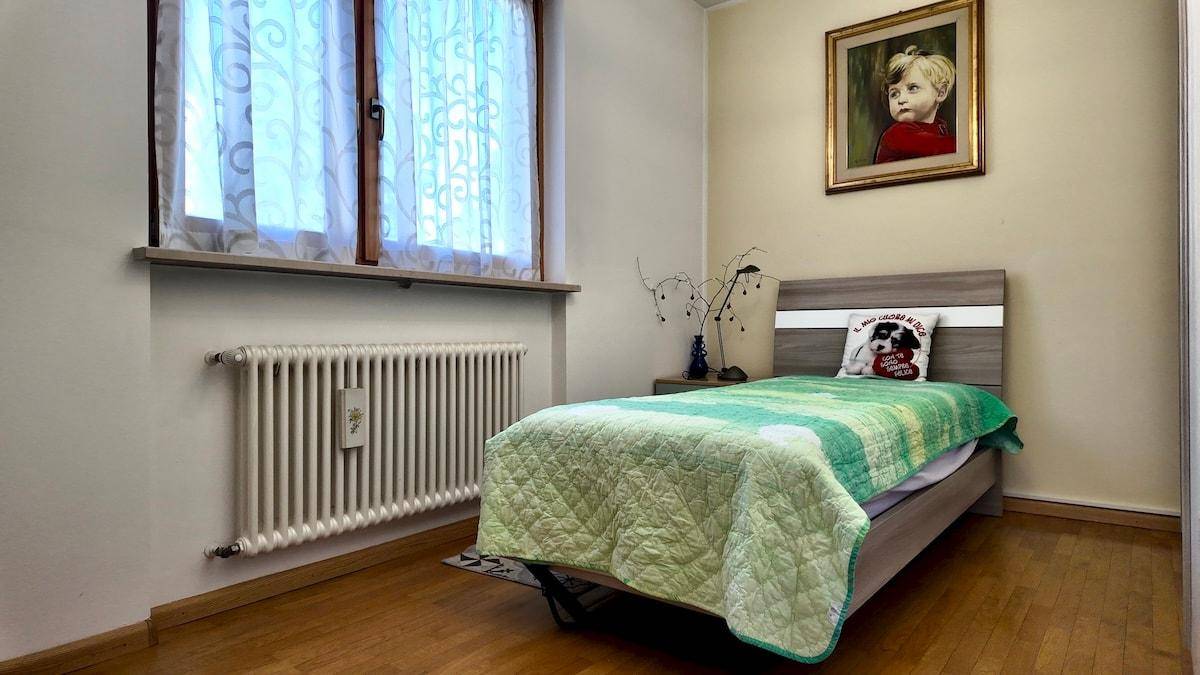 Kinderzimmer oder Gästezimmer mit Einzelbett, Holzfußboden und Fenster.