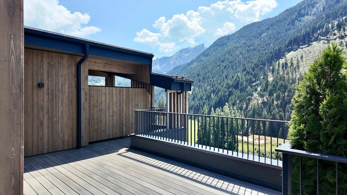 Geräumige Holzterrasse mit moderner Architektur und einem beeindruckenden Blick auf die umliegende Berglandschaft.