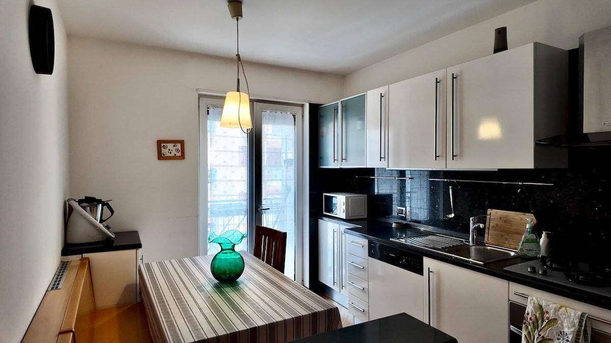 Helle Küche mit Essbereich, weißen Schränken und Zugang zu einem Balkon.