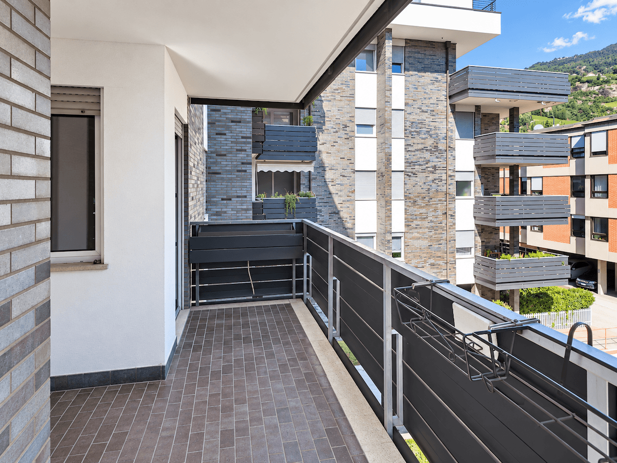Balkon mit Fliesenboden und Blick auf moderne Wohngebäude in der Umgebung.