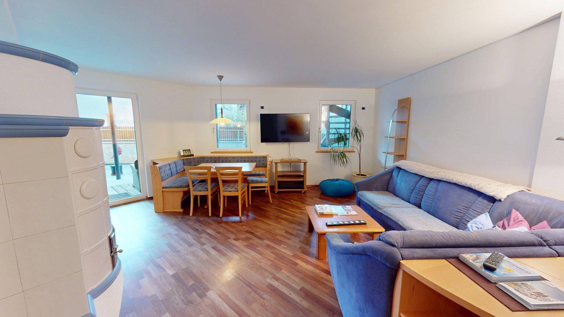Gemütlicher Wohn- und Essbereich mit Holzboden, Sitzbank und Zugang zur Terrasse.