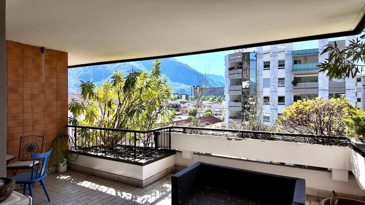 Geräumiger Balkon mit Sitzgelegenheiten und Panoramablick auf die Stadt und die Berge.