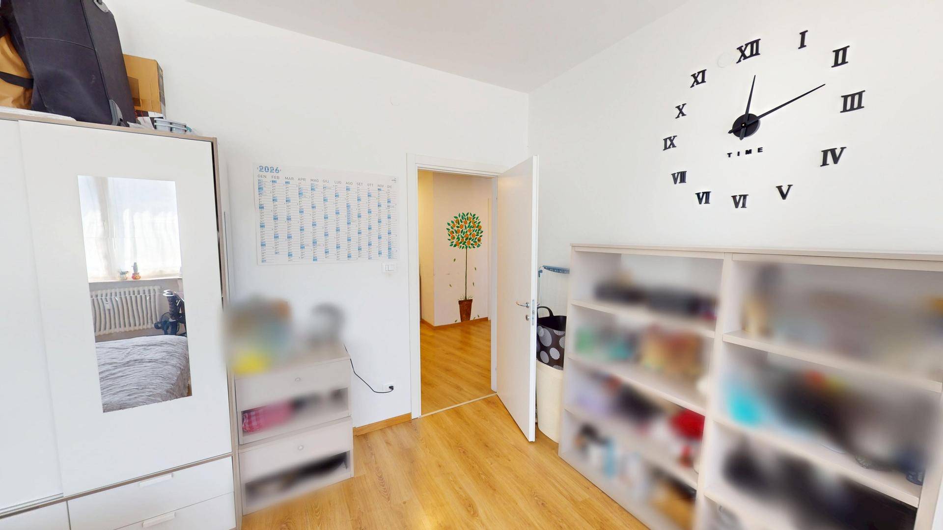 Schlafzimmer mit Holzboden, Kleiderschrank und dekorativer Wanduhr.